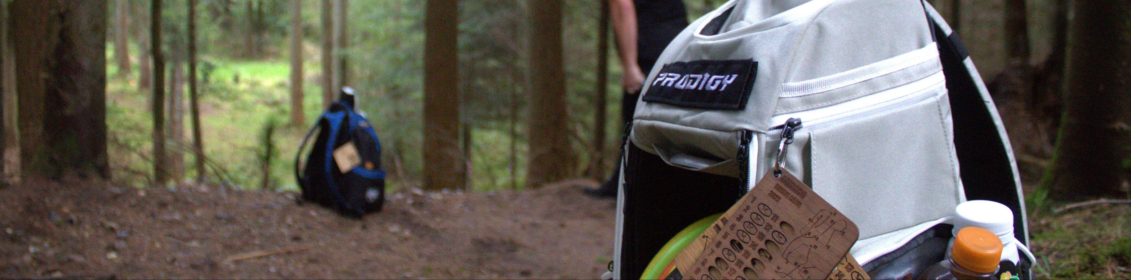 Birdie card on a disc golf bag with a disc golfer playing in the background